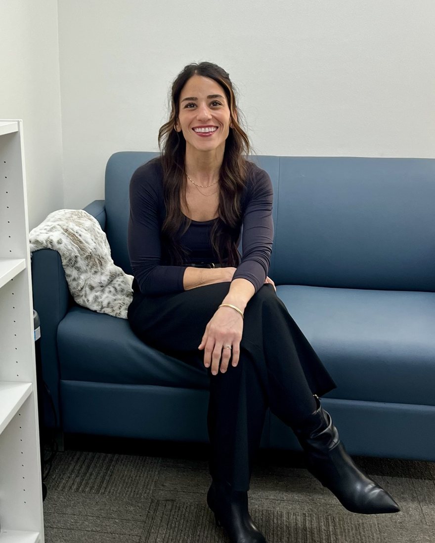 Anita Mazkoori smiling, seated on a blue sofa in a therapy office